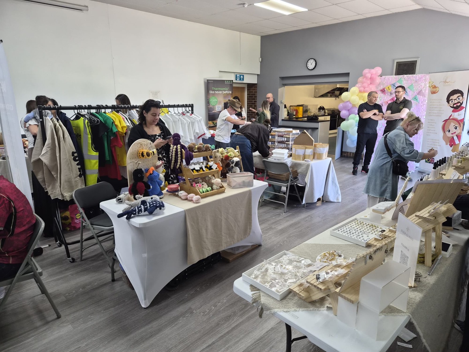 Busy hall with clothing rails and craft stalls