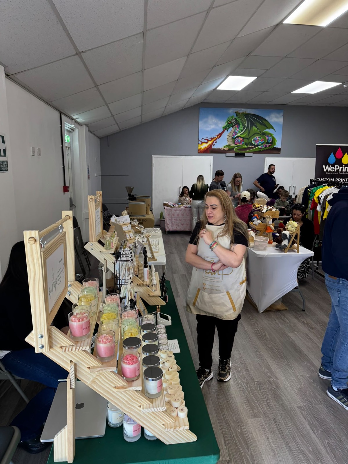 Handmade candles on a wooden display as visitors browse